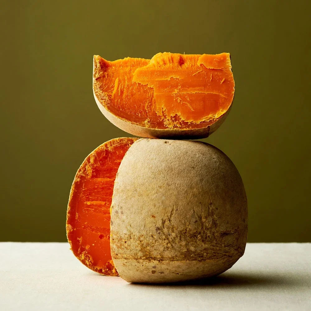 Ilustración de una bola de Mimolette y media bola naranja frente a una llanura de Flandes con molinos